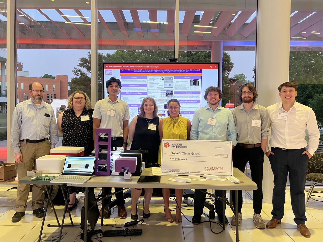 Drosophila team standing in front of the poster with John Poole